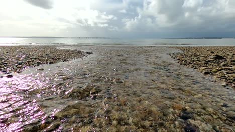 río costero que fluye sobre pebble beach hacia el mar del reino unido
