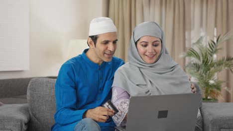 Happy-Muslim-couple-doing-online-shopping-on-laptop-using-credit-card