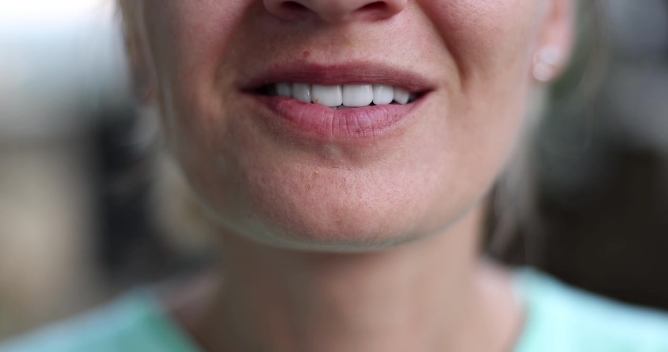 Donna addenta e mastica una noce sorridendo dolcemente in un'accogliente scena di degustazione