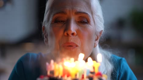 smiling aged birthday girl blowing candles on cake