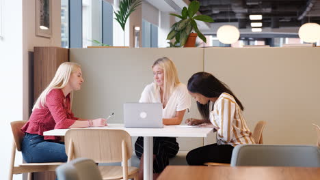 Gruppe-Junger-Geschäftsfrauen,-Die-Am-Tisch-Sitzen-Und-An-Der-Aufgabe-Mit-Einem-Laptop-Am-Tag-Der-Rekrutierungsbewertung-Für-Absolventen-Zusammenarbeiten