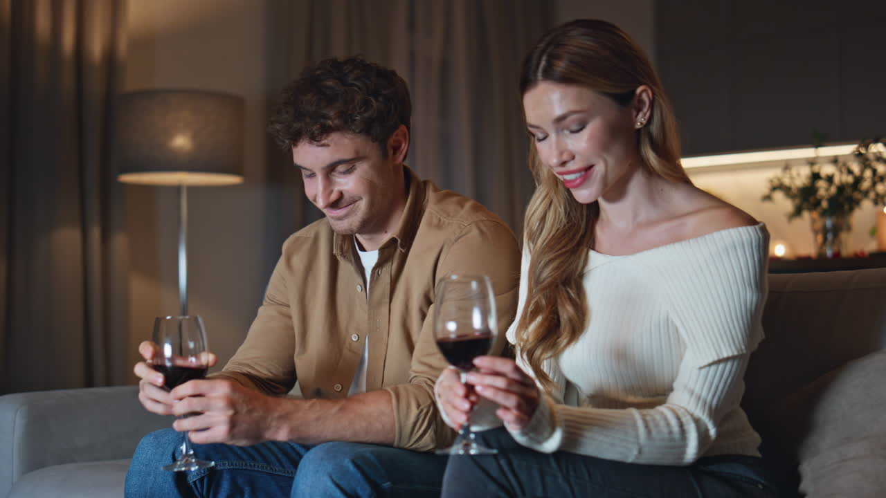 Shy couple have romantic date at cozy couch holding wine glasses close up.