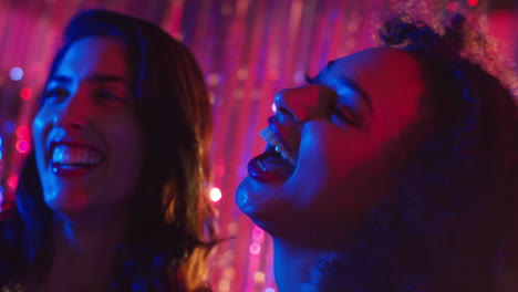 Portrait-Of-Two-Women-Friends-Having-Fun-Dancing-In-Nightclub-Bar-Or-Disco-With-Sparkling-Lights