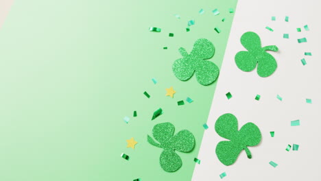 video of st patrick's green shamrock leaves with copy space on green to white background