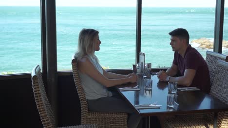 young attractive couple on date sitting at luxury restaurant with ocean view - bluff, new zealand