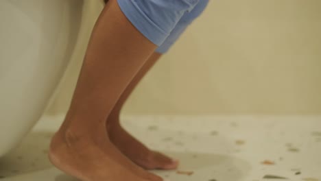 una vista discreta de una mujer sentada en un inodoro en un baño, con sólo sus piernas y parte inferior del cuerpo visible. la imagen se centra en la vida cotidiana y la privacidad en un entorno doméstico.