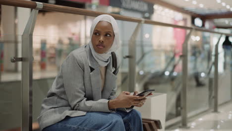 black lady uses public wifi with mobile phone in mall