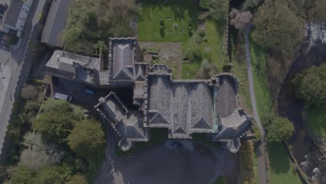 a flyover of birr castle right in front of birr town in co. offaly, surrounded by nature with trees, a lake and the town behind it