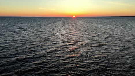 colorful sunset over a vast ocean, with a small boat silhouetted against the vibrant sky atlantic ocean at sunset, possibly near the coast of new jersey delaware, in the united states