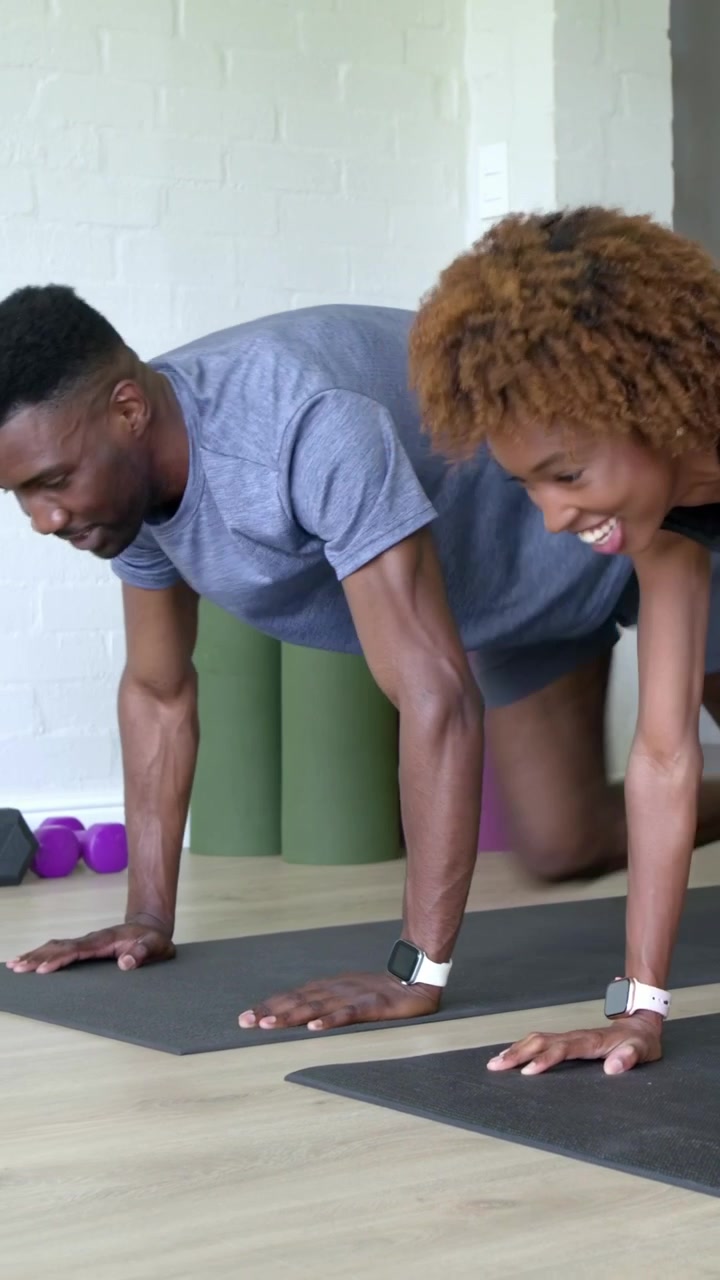 Vertical video: Leaning man coaching couple doing plank drives on mats at home in gear