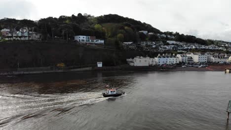 small trawler boat arriving into river teign with shaldon beach in background