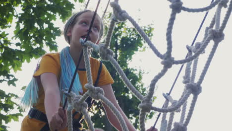 a child climbs ropes high in the trees - having fun in a rope city in an amusement park