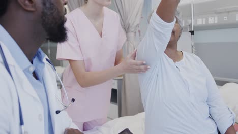 un médico masculino diverso con una tableta y una fisioterapeuta femenina tratando a una paciente femenina anciana feliz, en cámara lenta.