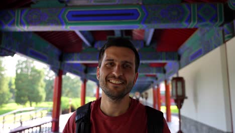 joyful man grinning under red and blue walkway at temple of heaven. beijing, china