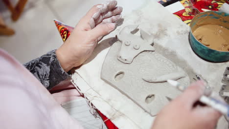 woman creating a clay cow figurine