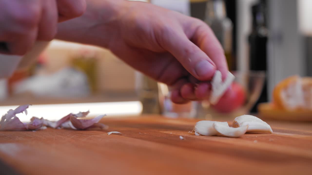 cook peels garlic on a wooden board