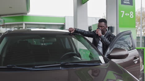man drinking coffee at a gas station