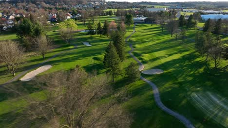 drone flight above green golf course in america during golden sunset