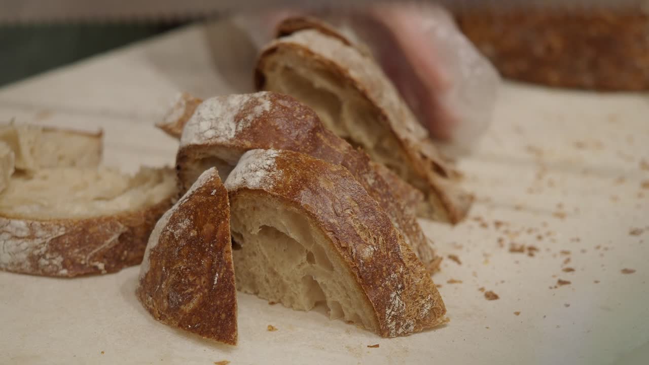 Primo piano di mani che tagliano pane artigianale fresco su un tagliere