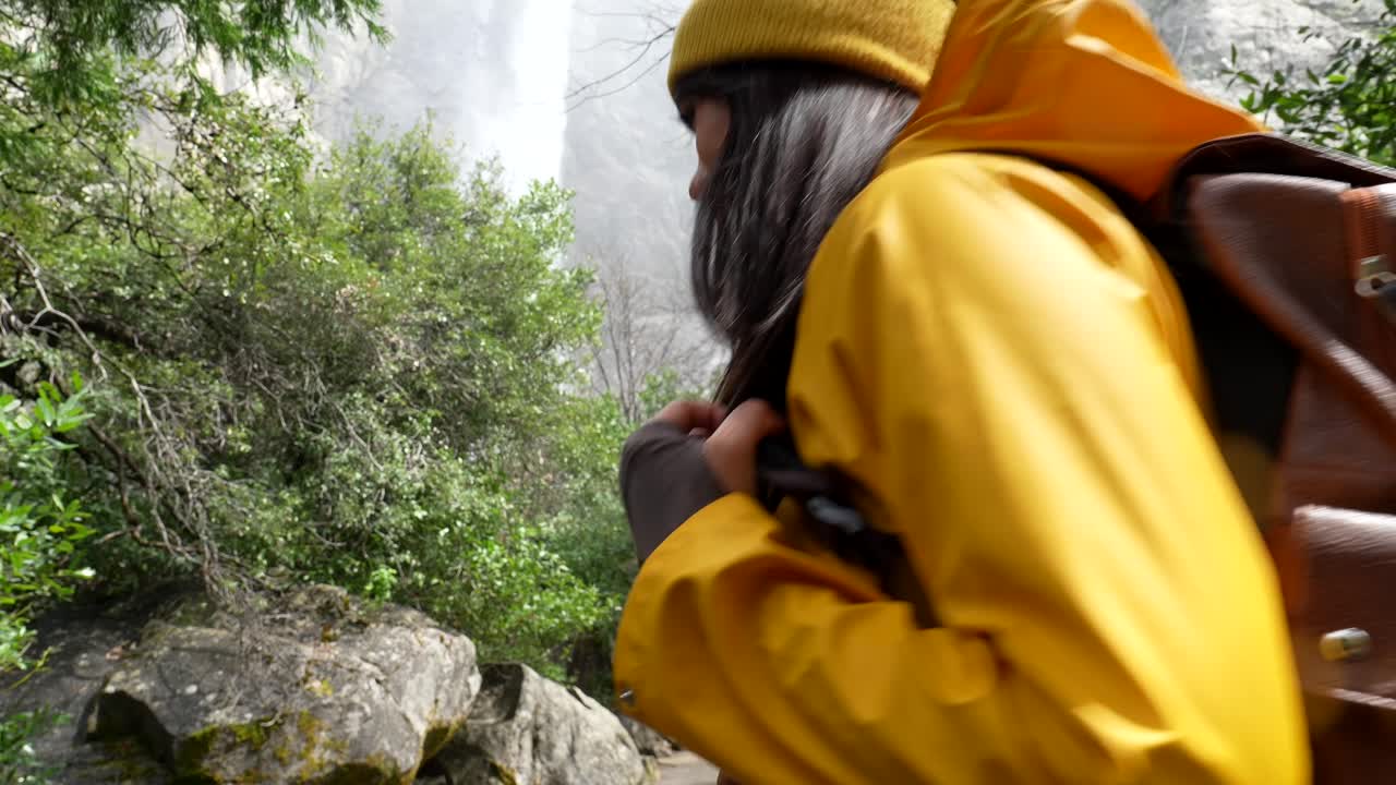 Smiling Woman Hiker with Backpack in Lush Forest Near Waterfall