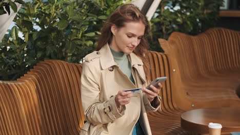 estudiante caucásica haciendo compras en línea en el teléfono inteligente al aire libre.