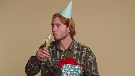 joven feliz con una caja de regalos de cumpleaños bailando, celebrando champán bebiendo un vaso en una fiesta de discoteca