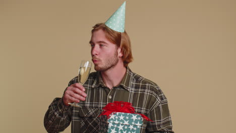 happy young man with birthday gift box dancing, celebrating champagne drinking glass on disco party