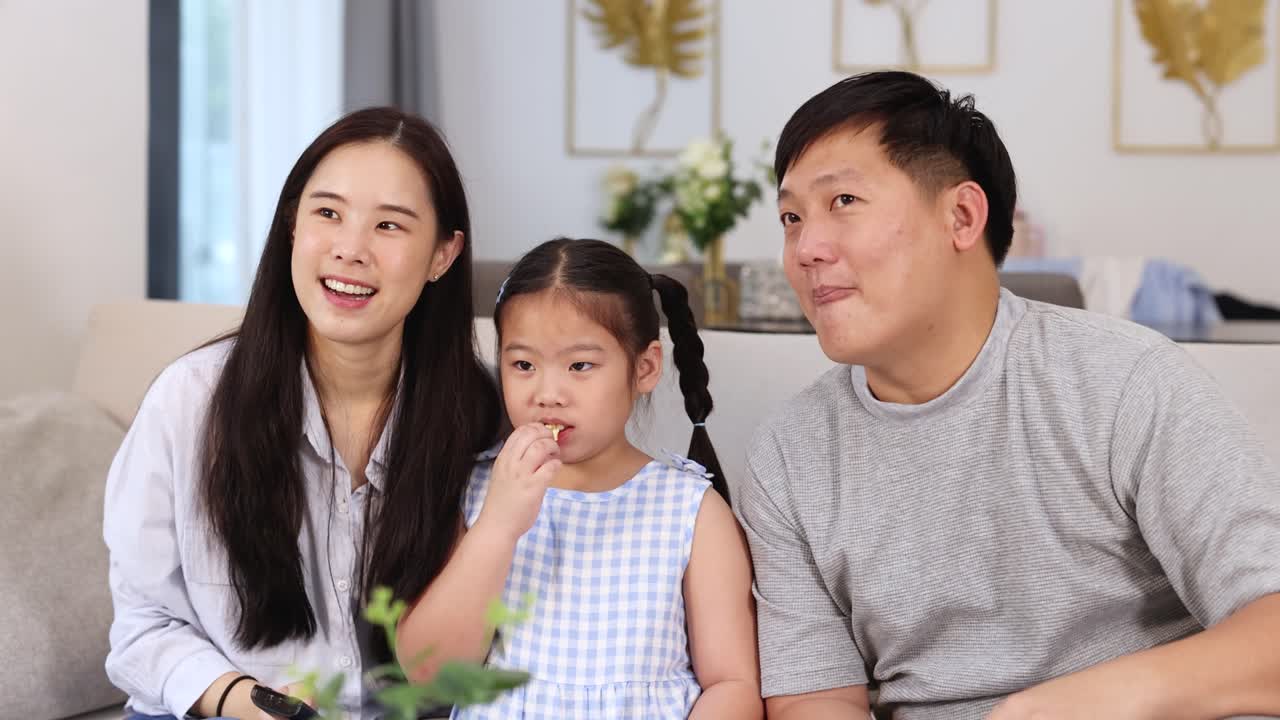 A joyful family moment with parents and child laughing together in a bright, cozy living room setting