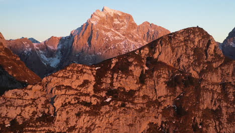 cinematic drone shot moving past a rock cliff, then focusing on mangart mountain in slovenia