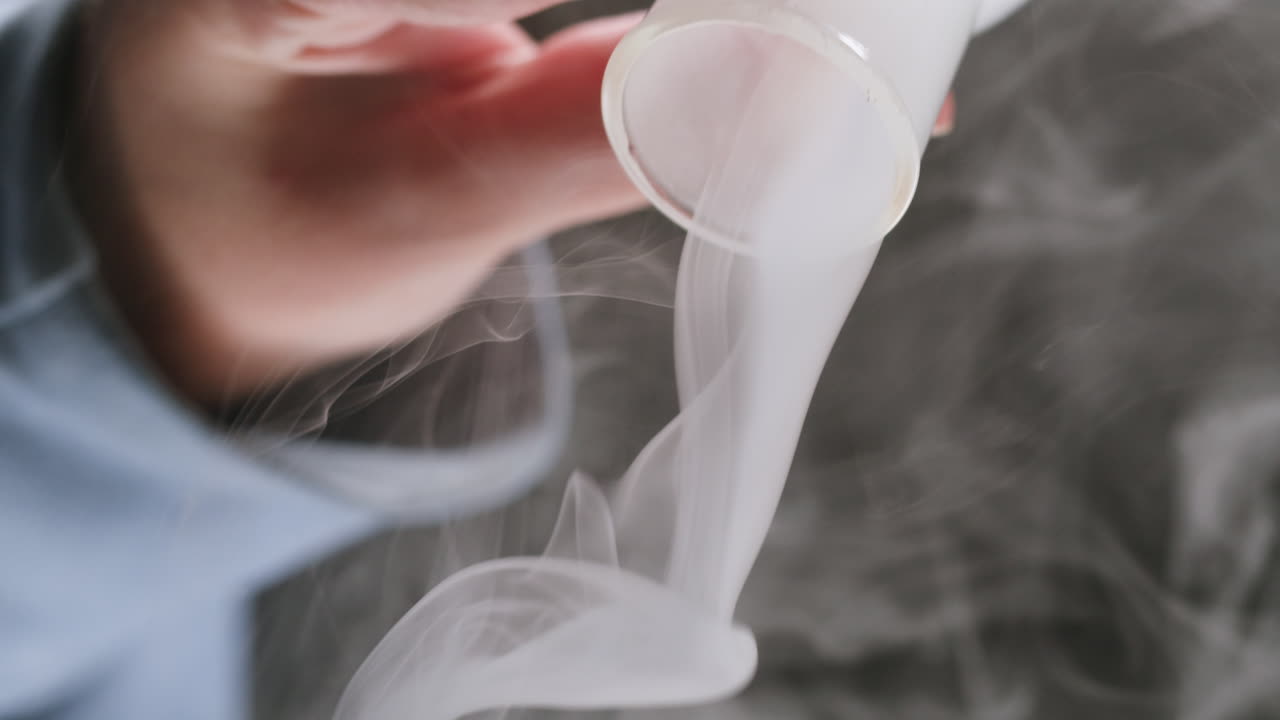 Close-up of Hand Pouring White Smoke from Glass Tube