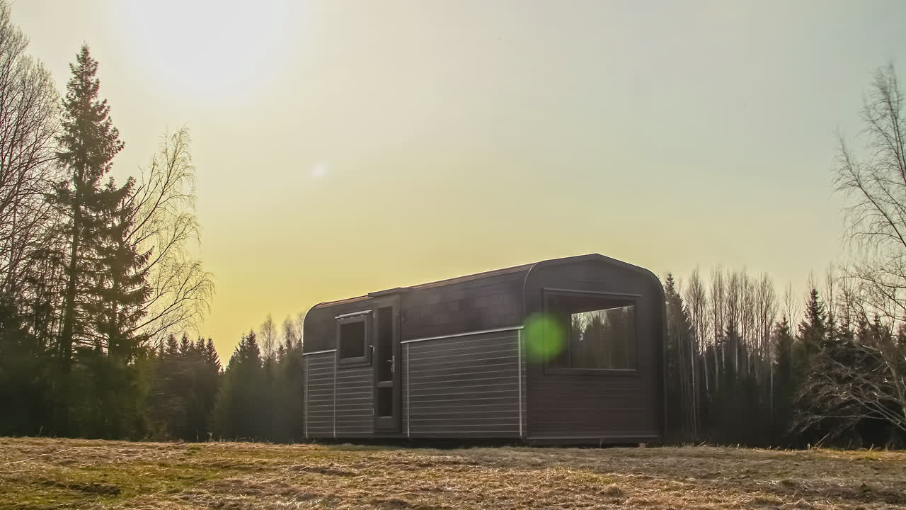 Vakker soloppgang i morgengryet i et landlig skogsområde med en tømmerhytte etter en frostnatt