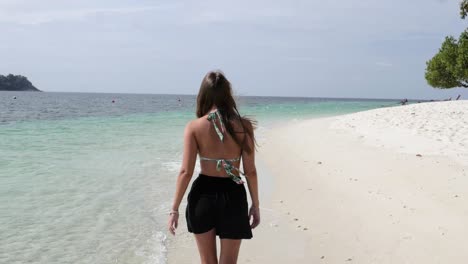 Ultra-slow-motion-shot-of-young-caucasian-woman-walking-on-beautiful-beach-on-island-in-Thailand