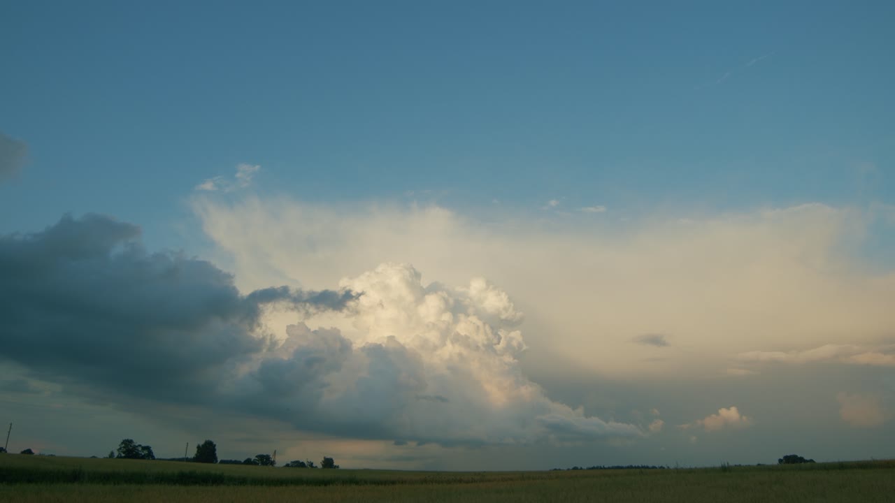 Rain clouds cumulus stratocumulus time lapse over countryside fields in pure sunset light
