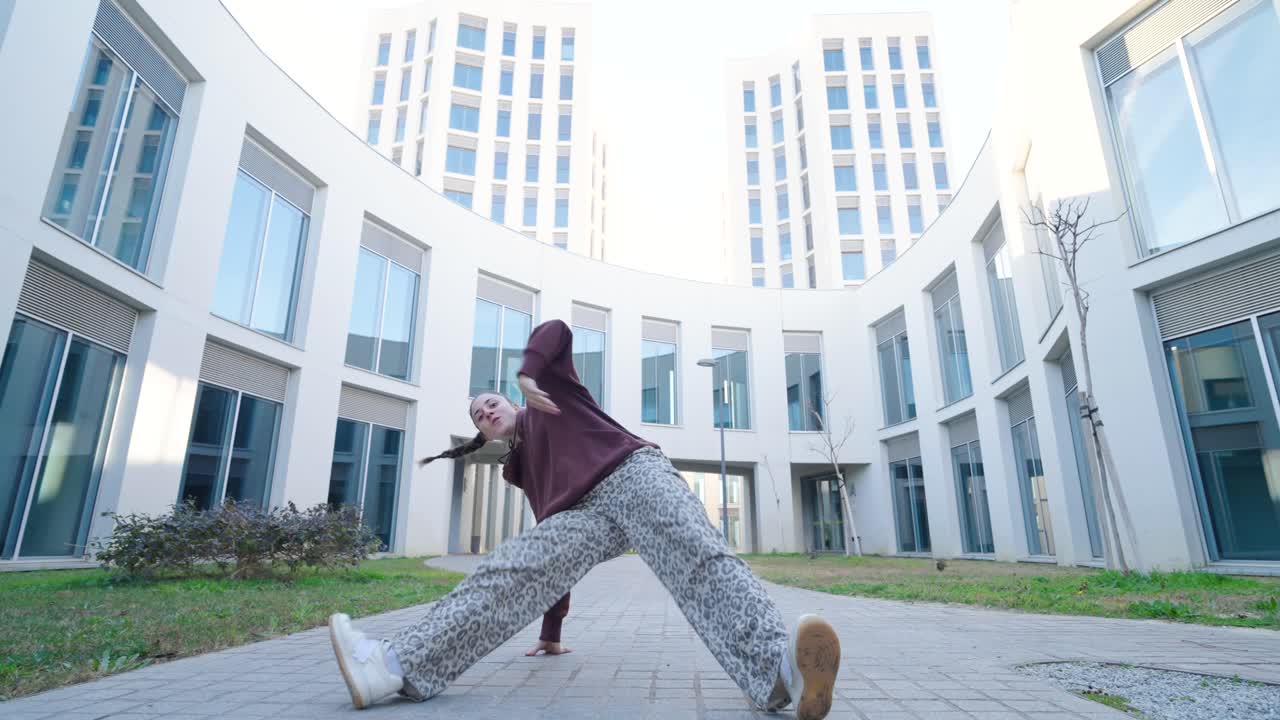 Açık havada modern dans figürleri sergileyen genç enerjik kadın dansçı.