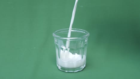 pouring fresh milk in slow motion into a transparent glass with a green screen background