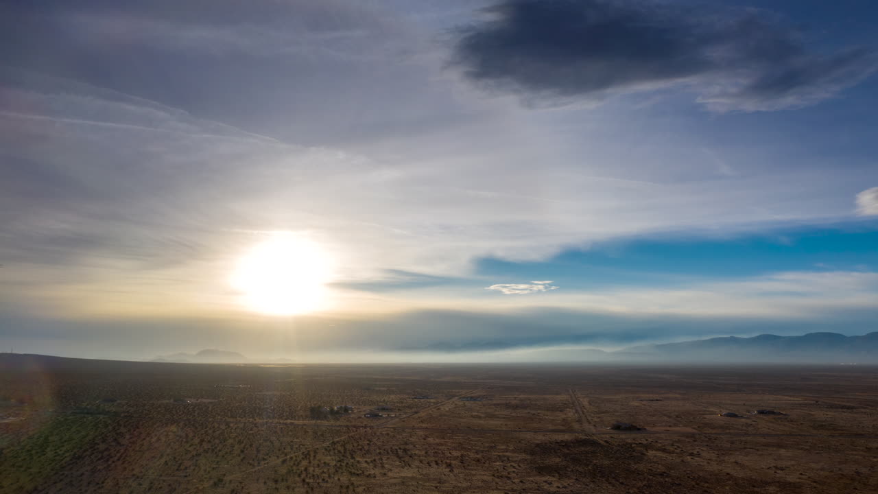 Wispy veil of clouds cross the desert as the bright sun heats up the arid landscape - aerial hyper lapse