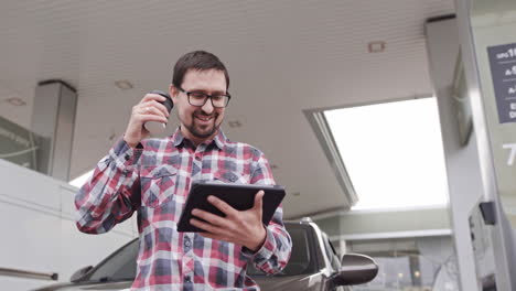 man using tablet at gas station
