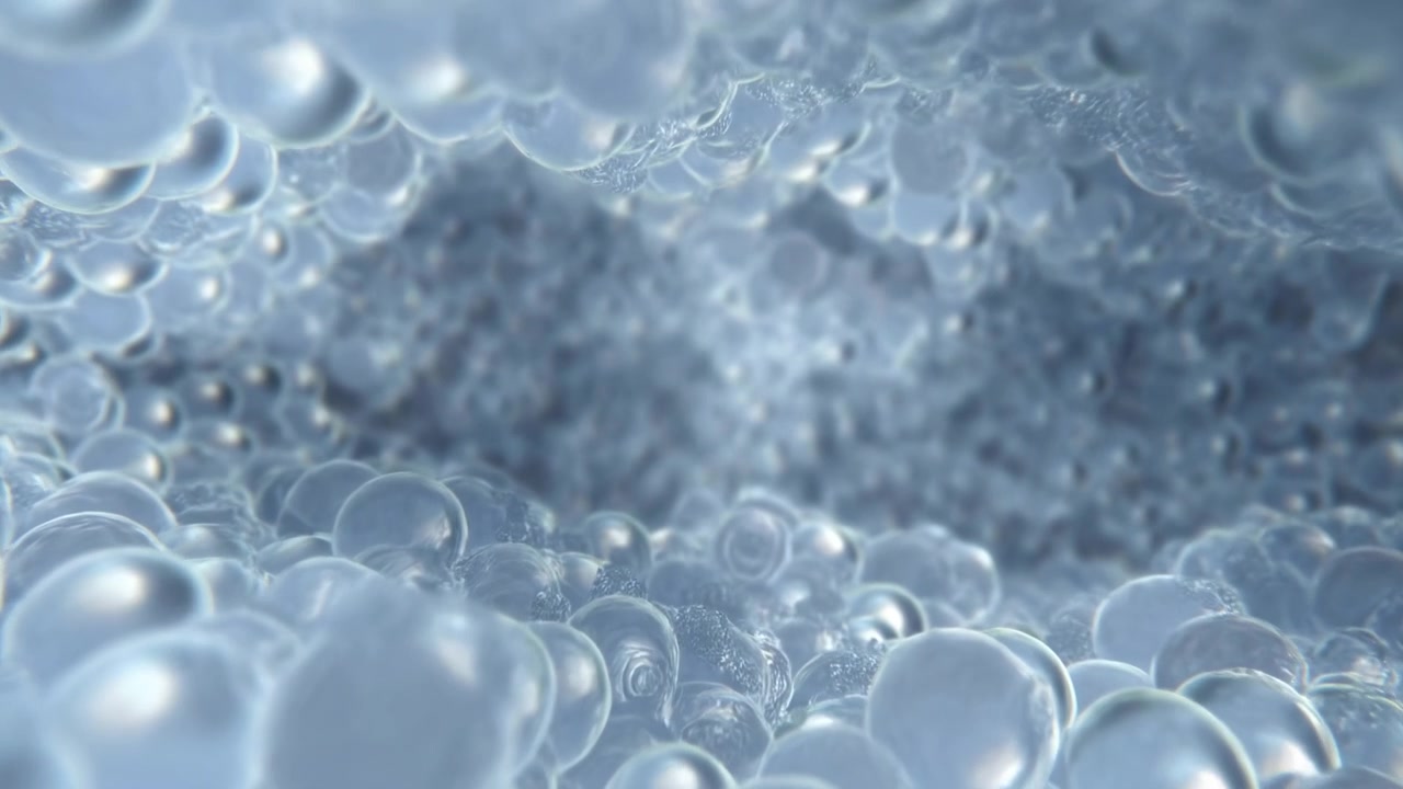 Bolle trasparenti piccole e grandi si riorganizzano delicatamente all'interno di una superficie schiumosa azzurra pallida, mentre i riflessi luminosi delineano forme arrotondate e una banda più scura e texturizzata rimane visibile al centro.