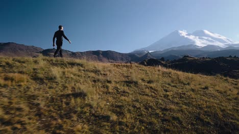 el tipo subió una colina y mira hacia una montaña alta en la que hay nieve. el tipo delante del pico nevado.