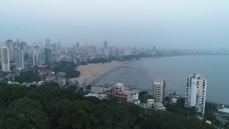 Una-Toma-Cinematográfica-De-Drones-Del-Famoso-Punto-De-Playa-Chaupati-De-Marine-Drive-En-La-Región-Sur-De-Bombay-De-La-Ciudad-De-Mumbai,-Con-Vistas-A-La-Colina-Del-Jardín-Colgante-Y-Al-Bosque-En-Cámara-Lenta