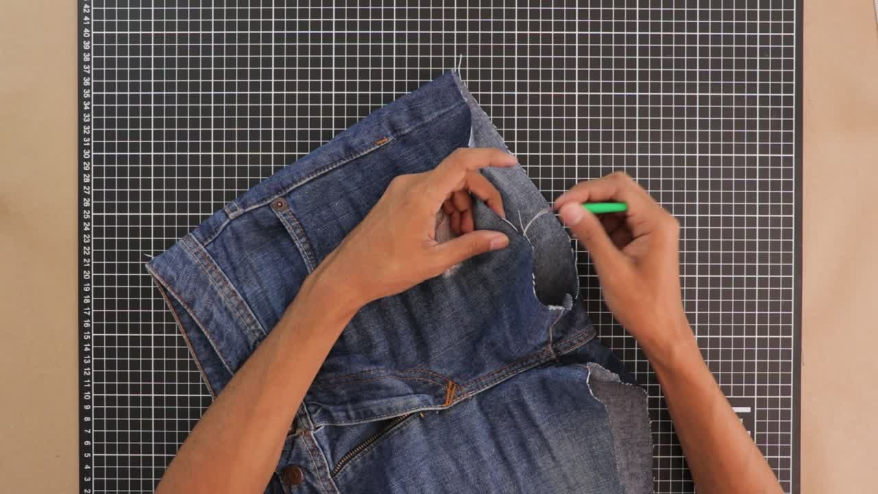 Person remodeling trousers with unpicking punch. Close up
