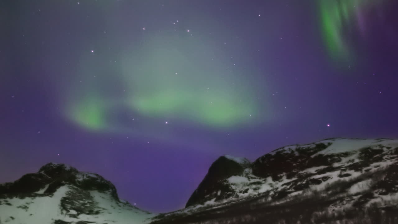 aurora boreal brillante bailando sobre un paso de montaña, panorámica lenta de izquierda a derecha