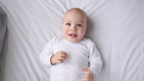 beautiful baby on back on bed, top view