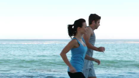 couple running side by side on the beach