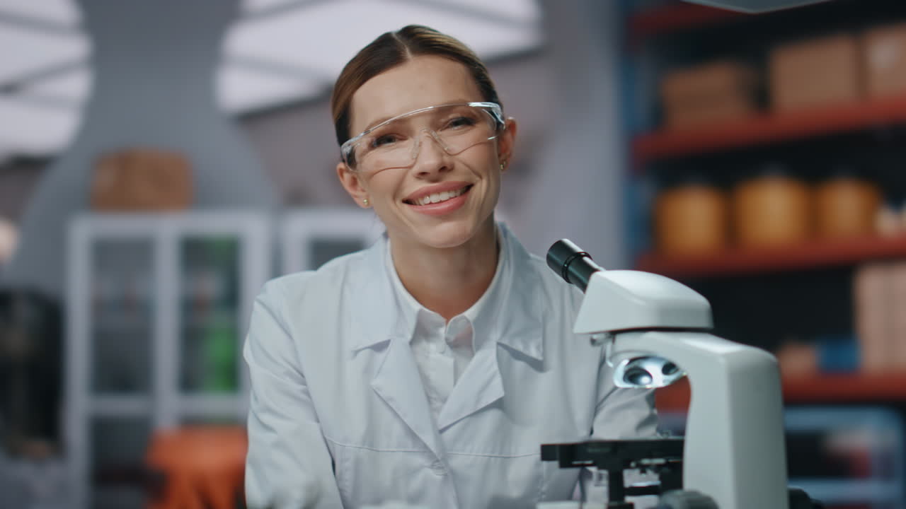 Successful chemist looking microscope in scientific modern laboratory close up.