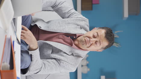 vertical video of home office worker old man nods to the camera.