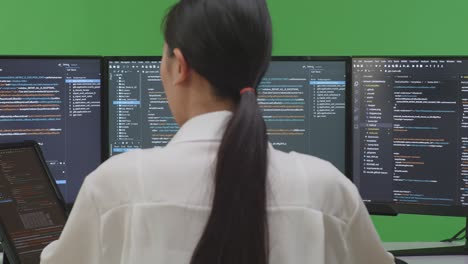 woman coding on multiple computer screens