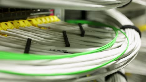 Handheld-shot-following-white-and-green-cables-in-a-data-center,-server-room