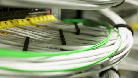 handheld shot following white and green cables in a data center, server room