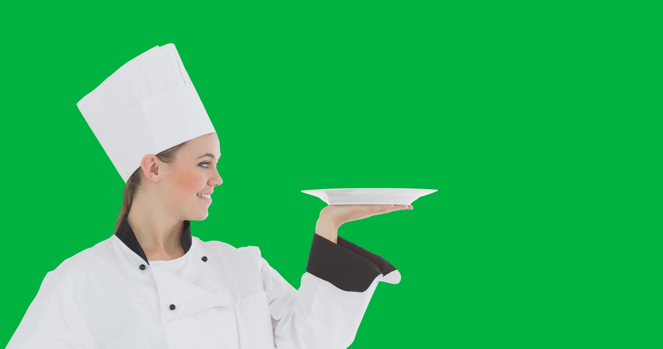 Chef donna caucasica sorridente che tiene un piatto su sfondo nero